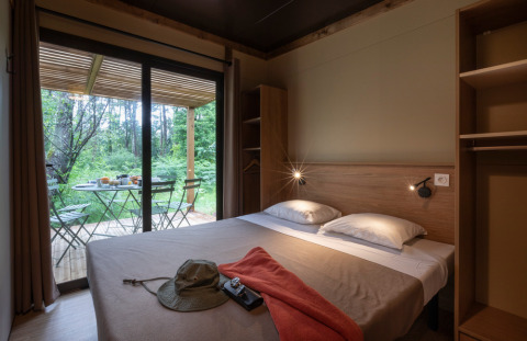 Dormitorio en Chalet Ottawa en Huttopia Wattwiller, Francia, con terraza y vista a la naturaleza exterior.