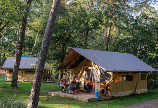 Tienda safari Canadienne Tent II en Huttopia Lac de Serre Ponçon, Francia, familias disfrutan el exterior.