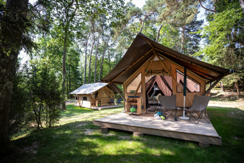 Tienda safari Canadienne Tent II en Huttopia Lac de Serre Ponçon, Francia, rodeada de frondosos bosques verdes.