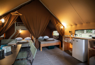 Interno della Canadienne Tent II con letti, cucina e area pranzo a Huttopia Lac de Serre Ponçon, Francia.