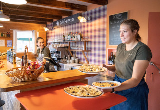 Twee serveersters brengen eten naar klanten in het restaurant van Huttopia Wattwiller, Grand Est, Frankrijk.