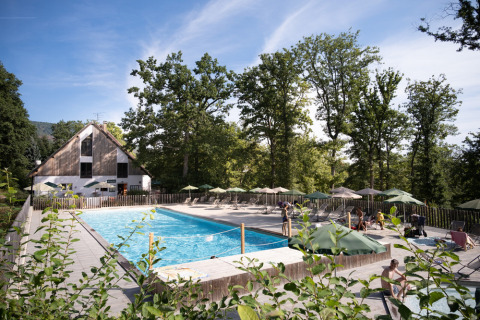 Piscina al aire libre con sombrillas y tumbonas en el parque vacacional Huttopia Wattwiller, Grand Est, Francia.