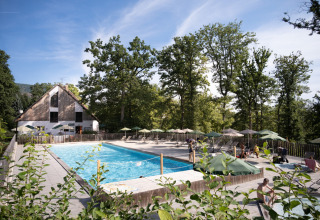 Außenpool mit Liegestühlen und Sonnenschirmen im Ferienpark Huttopia Wattwiller, Grand Est, Frankreich.