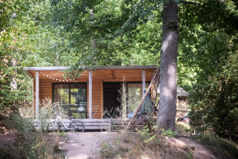 Cabaña de madera rodeada de árboles en Huttopia Wattwiller, un parque vacacional en Grand Est, Francia.