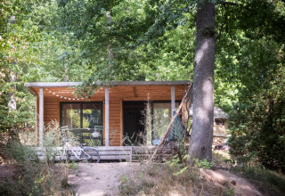 Holzhütte im Wald bei Huttopia Wattwiller, einem Ferienpark in Grand Est, Frankreich, mit Fahrrad davor.