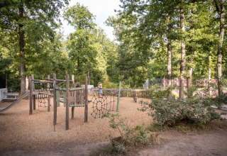 Kinderspeelzone omringd door bomen bij Huttopia Wattwiller vakantiepark in Grand Est, Frankrijk.