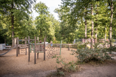 Aire de jeux pour enfants entourée d’arbres au parc de vacances Huttopia Wattwiller, Grand Est, France.