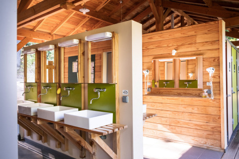 Instalaciones de baño comunales modernas con detalles de madera en Huttopia Wattwiller, Grand Est, Francia.