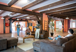 Mensen relaxen in de gezellige lounge van het Huttopia Wattwiller vakantiepark in Grand Est, Frankrijk.
