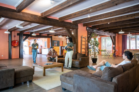 Mensen relaxen in de gezellige lounge van het Huttopia Wattwiller vakantiepark in Grand Est, Frankrijk.