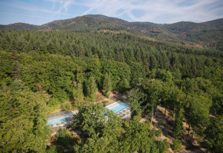 Vista aerea del parco vacanze Huttopia Wattwiller in Grand Est, Francia, immerso tra boschi e colline.