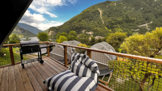 Udsigt fra Big Oak Lodge-safari teltets terrasse med grill, liggestol og smukke bjerge i baggrunden.