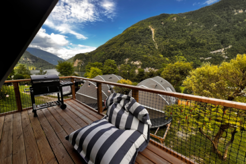 Zicht vanaf het terras van de Big Oak Lodge safaritent met barbecue, zitzak en groene bergen rondom.