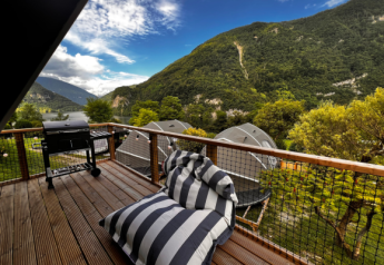 Zicht vanaf het terras van de Big Oak Lodge safaritent met barbecue, zitzak en groene bergen rondom.
