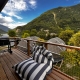 Udsigt fra Big Oak Lodge-safari teltets terrasse med grill, liggestol og smukke bjerge i baggrunden.