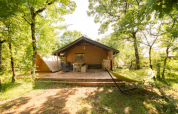 Tienda Safari Lodge + Teeny Lodge en Camping Les 3 Cantons, Francia, rodeada de árboles verdes.