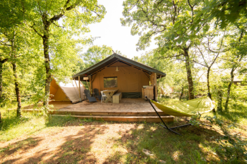 Tienda Safari Lodge + Teeny Lodge en Camping Les 3 Cantons, Francia, rodeada de árboles verdes.