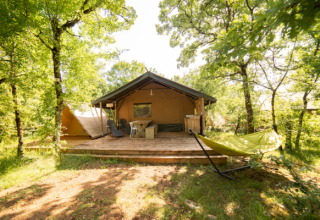 Tienda Safari Lodge + Teeny Lodge en Camping Les 3 Cantons, Francia, rodeada de árboles verdes.