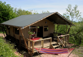 Safari tent Wood Lodge bij Camping Casa Tartufo in Italië met houten veranda en kleurrijke hangmat.