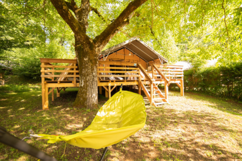 Safari Lodge + Teeny Lodge safari tent at Camping Les Tailladis, France, with wooden deck and yellow hammock shade.