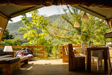 View from a luxury safari tent, Desert Lodge, with rustic wood furniture and lush green mountain scenery.