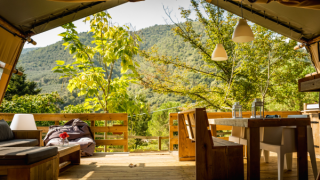View from a luxury safari tent, Desert Lodge, with rustic wood furniture and lush green mountain scenery.