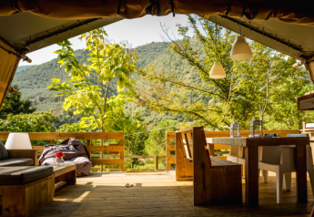 Vista desde una tienda safari Desert Lodge con mobiliario rústico de madera y paisaje montañoso verde.
