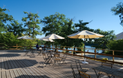 Udendørs terrasse med parasoller og borde ved en sø i Camping Seasonova L'Etang des Bois, Centre-Val de Loire.