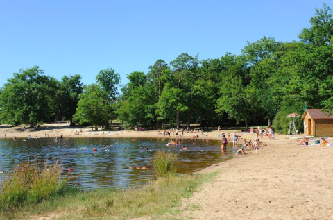 Beach and lake with people swimming and relaxing at Camping Seasonova L'Etang des Bois, Centre-Val de Loire, France.
