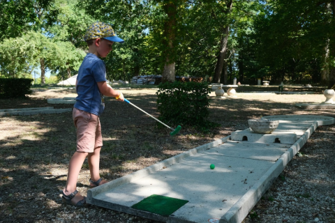 Jongen speelt minigolf buiten bij Camping Seasonova L'Etang des Bois in Centre-Val de Loire, Frankrijk.