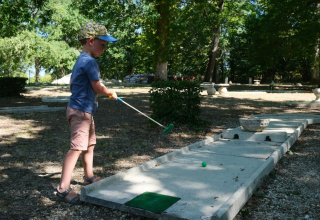 Jongen speelt buiten minigolf bij Camping Seasonova L'Etang des Bois in Centre-Val de Loire, Frankrijk.