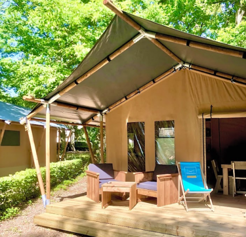 Ein Glamping-Zelt mit Holzterrasse, Holzsesseln und Liegestuhl im Camping Seasonova L'Etang des Bois in Frankreich.