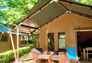 Glamping tent met houten meubels en strandstoel op houten veranda bij Camping Seasonova L'Etang des Bois, Frankrijk.