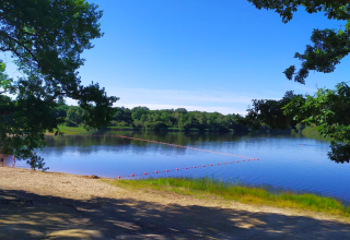 Lago tranquillo circondato da alberi e spiaggia sabbiosa vicino a Vieilles-Maisons-sur-Joudry, Centre-Val de Loire.