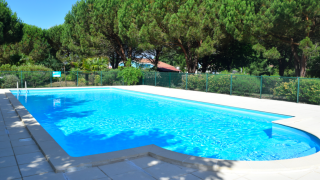 Buitenzwembad bij Village Seasonova Bassin d'Arcachon vakantiepark, omgeven door bomen in Nouvelle-Aquitaine, Frankrijk.