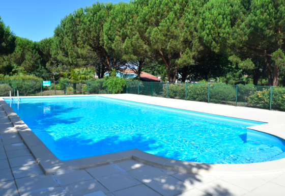 Udendørs swimmingpool i ferieparken Village Seasonova Bassin d'Arcachon, omgivet af grønne træer, Nouvelle-Aquitaine.