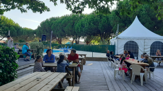 Zona de comedor al aire libre con mesas de madera y familias en Village Seasonova Bassin d'Arcachon.