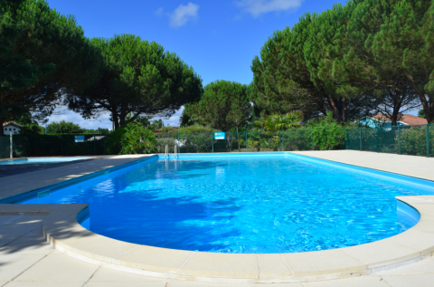 Piscina al aire libre rodeada de árboles verdes en el parque vacacional Village Seasonova Bassin d'Arcachon, Francia.