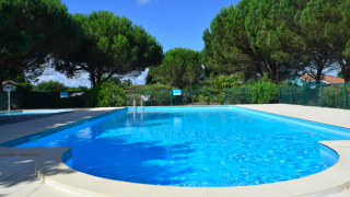 Piscina al aire libre rodeada de árboles verdes en el parque vacacional Village Seasonova Bassin d'Arcachon, Francia.