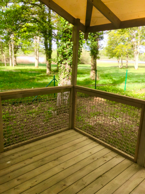 Zicht vanaf de houten veranda van de Prestique cabine op Camping Seasonova L'Etang des Bois, Frankrijk.