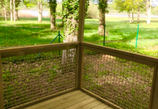 Zicht vanaf de houten veranda van de Prestique cabine op Camping Seasonova L'Etang des Bois, Frankrijk.