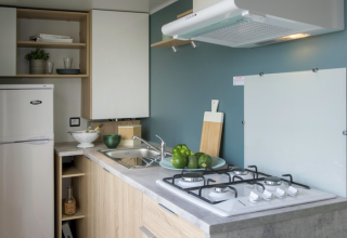 Cocina de cabaña moderna con frigorífico y fogones en Camping Seasonova L'Etang des Bois, Francia.