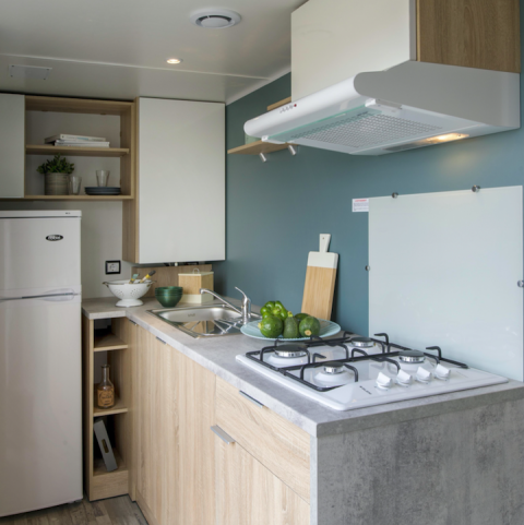 Cocina de cabaña moderna con frigorífico y fogones en Camping Seasonova L'Etang des Bois, Francia.
