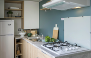 Cuisine moderne d'une cabane avec frigo et plaques de cuisson au Camping Seasonova L'Etang des Bois en France.