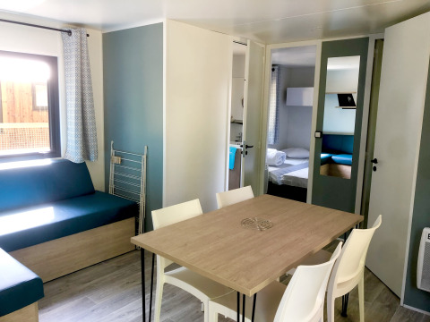 Zona pranzo e soggiorno della cabina Prestique presso Camping Seasonova L'Etang des Bois in Francia.