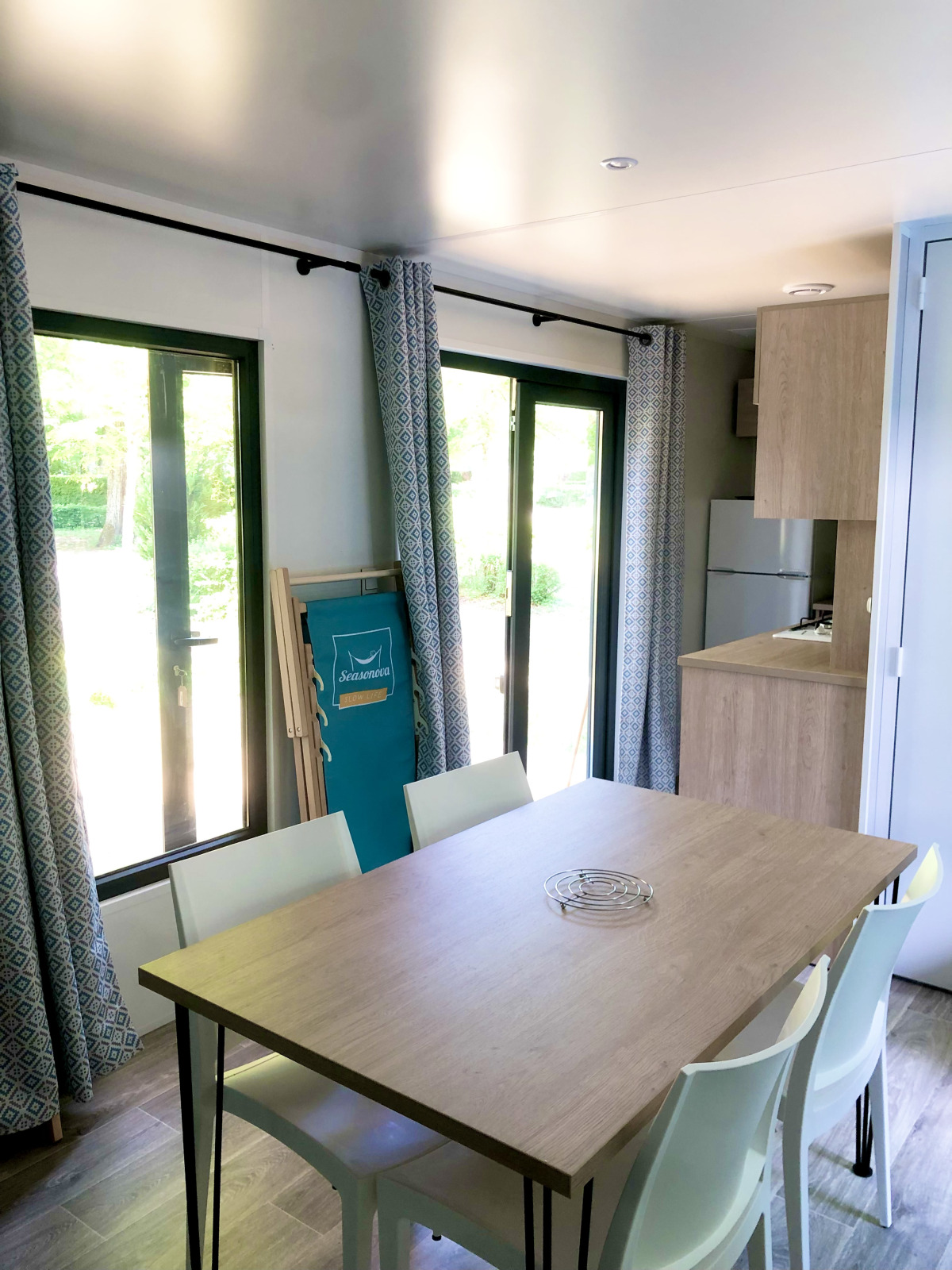 Lichte eetruimte in de Prestique-hut bij Camping Seasonova L'Etang des Bois, Frankrijk, met moderne inrichting.