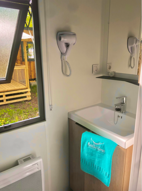 Bagno moderno nella cabina Prestige al Camping Seasonova L'Etang des Bois in Francia, con lavabo e phon.