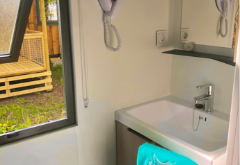 Moderne badkamer in Prestige-hut op Camping Seasonova L'Etang des Bois met wastafel en föhn.