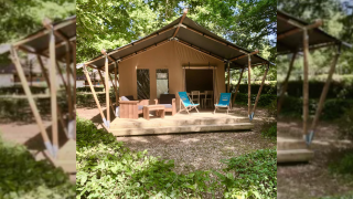 Tienda safari Slow Lodge con terraza de madera, sillas y entorno natural rodeado de árboles verdes.