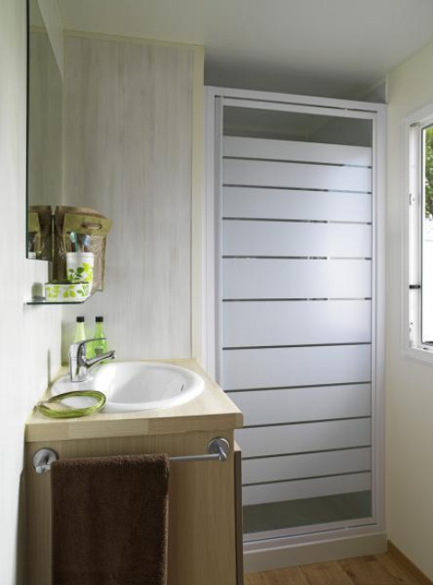 Modernes Badezimmer in einer Glamping-Unterkunft mit Dusche, Waschbecken, Spiegel und Fenster.